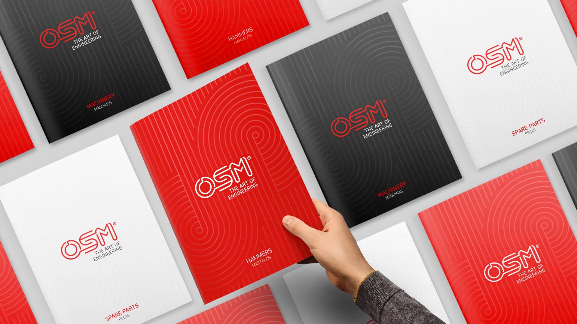 A hand reaches for a red brochure titled "HAMMERS," surrounded by various OSM engineering booklets.